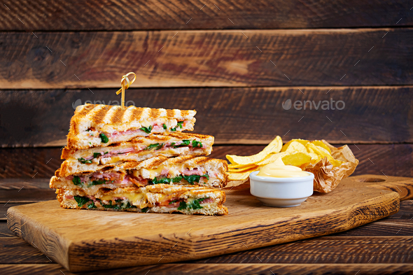 Club sandwich with ham, cheese, tomato, salad and chips
