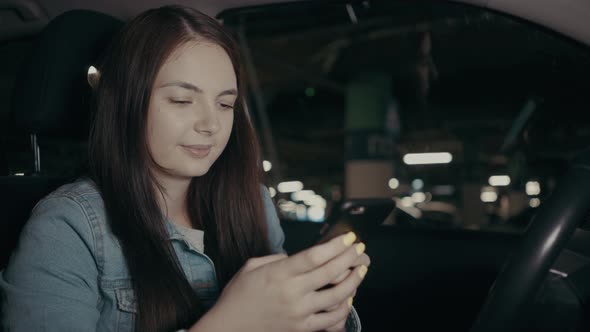 Woman Uses an Application on His Phone While Sitting in the Car in the Parking Lot alt