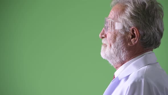 Handsome Senior Bearded Man Doctor Against Green Background alt