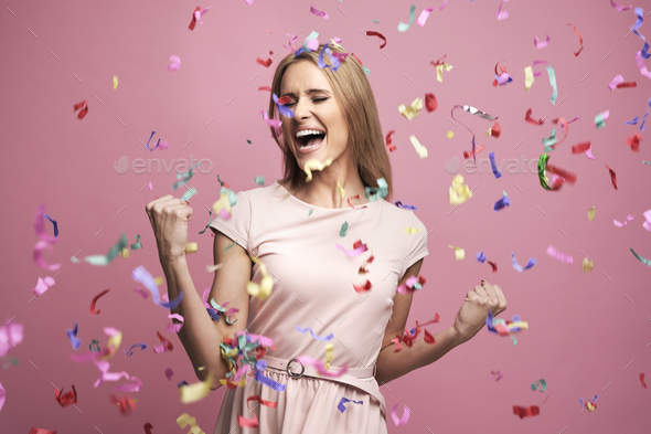 Studio shot of successful young woman celebrating achievement with confetti - Stock Photo - Images