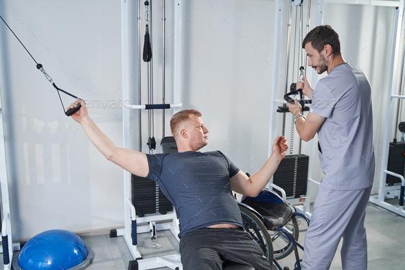 Young man with disability training in rehab gym. Patient with handicap