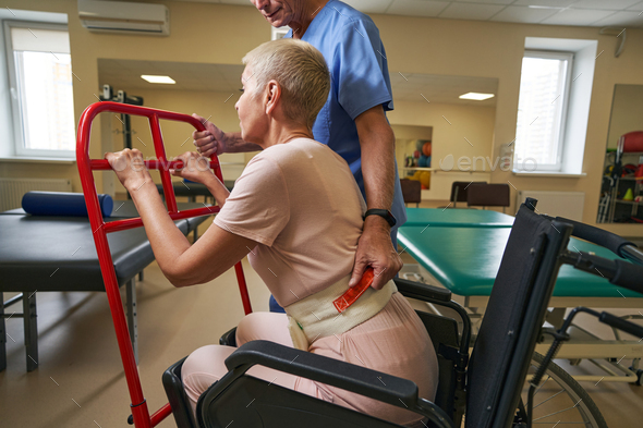 Physiotherapist teaching disabled woman to use walker at recovery center