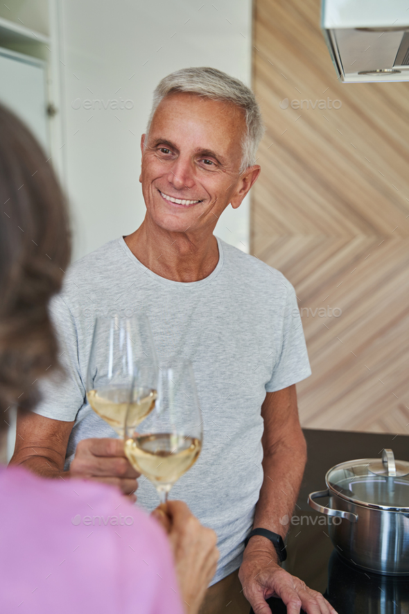 Elderly husband drinking alcohol from glass with his wife Stock Photo by Iakobchuk