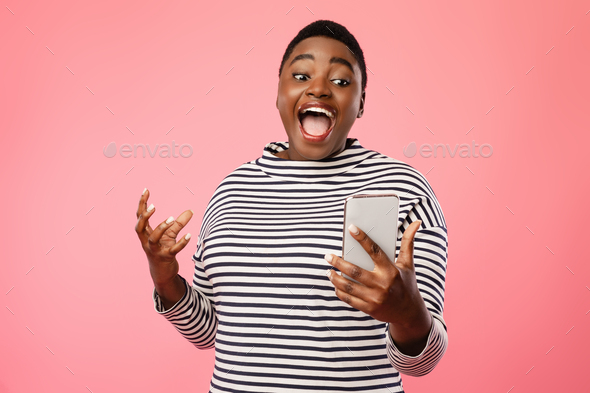 Excited Overweight Black Female Looking At Smartphone On Pink ...