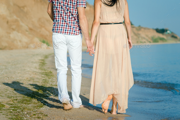 a guy and a girl walk along the seashore