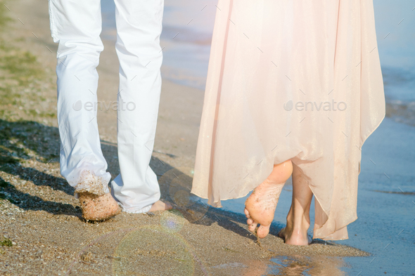 a guy and a girl walk along the seashore