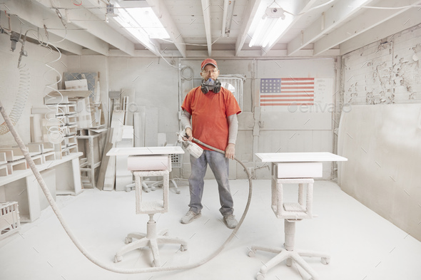 Portrait of cabinet maker with spray gun in workshop spray booth