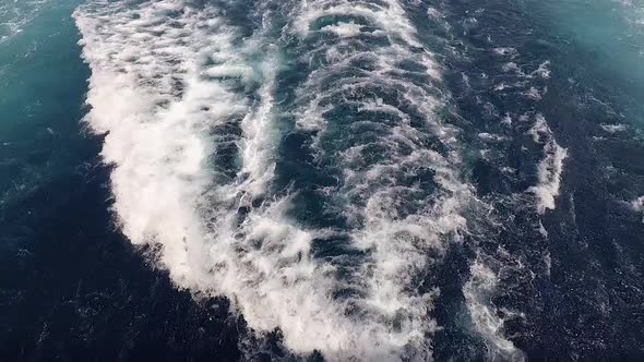 Ship wake on the ocean. Water foam trace behind the large ship goes till the horizon.