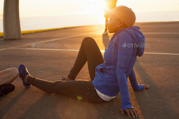 Young woman sitting on basketball court, outdoors