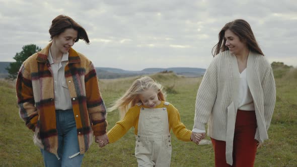 Two Loving Women Holding Hands with Cute Daughter Outdoors alt