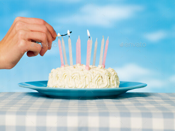 A person lighting matches on a cake