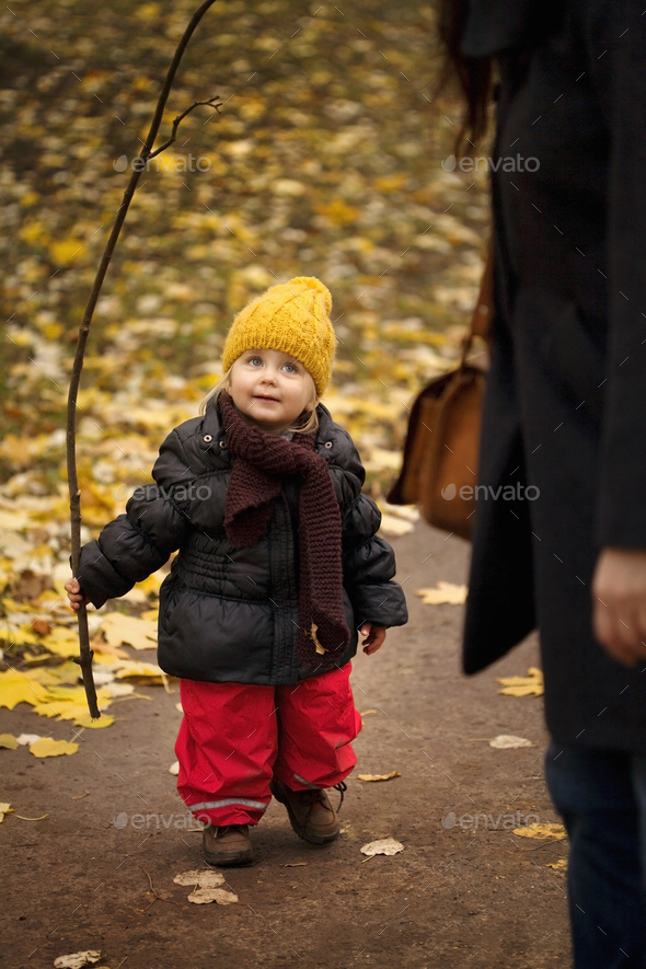 Young girl on walk wearing winter clothes, holding stick