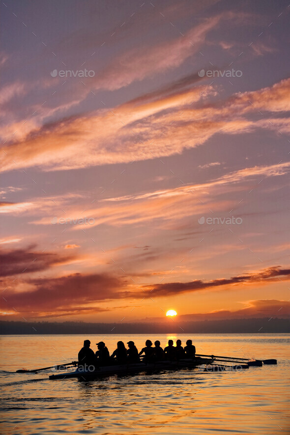 Eight people rowing at sunset