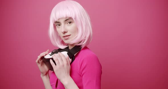 Woman Uses a Virtual Reality Glasses on Isolated Pink Background alt