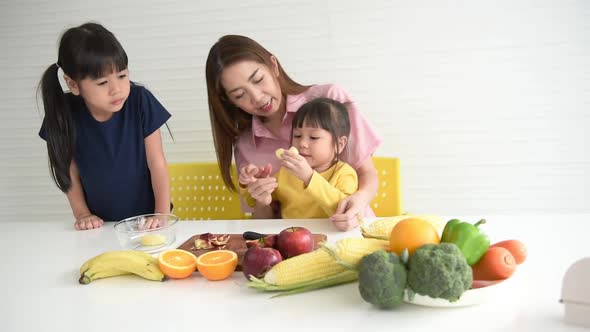Asian mother, feeding apple fruits for her two daughters alt