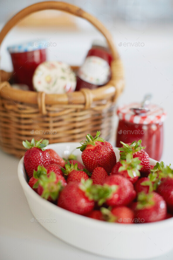Bowl of strawberries with jars of jelly