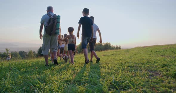 Happy Kids and Father Walking Down Green Hill Sun Rays alt
