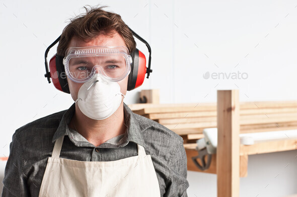 Carpenter wearing dust mask and ear defenders, portrait