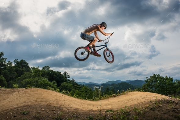 Young man doing BMX trick on rural pump track