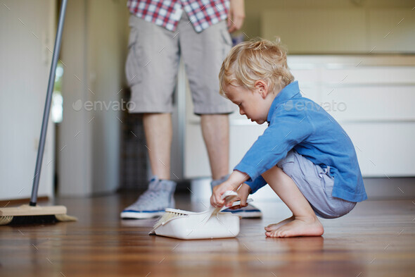 Boy helping father sweep floor