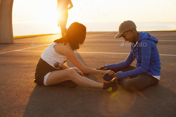 Two women sitting on basketball court, outdoors