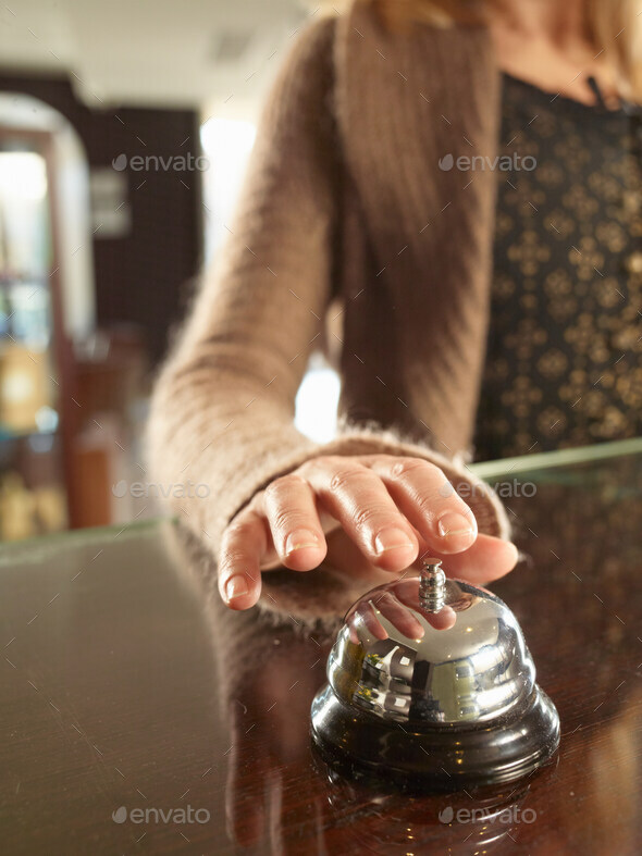 Close up of woman ringing a hotel porters bell - Stock Photo - Images