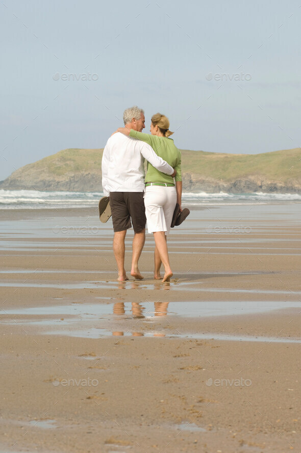 Couple walking arm in arm on a beach - Stock Photo - Images