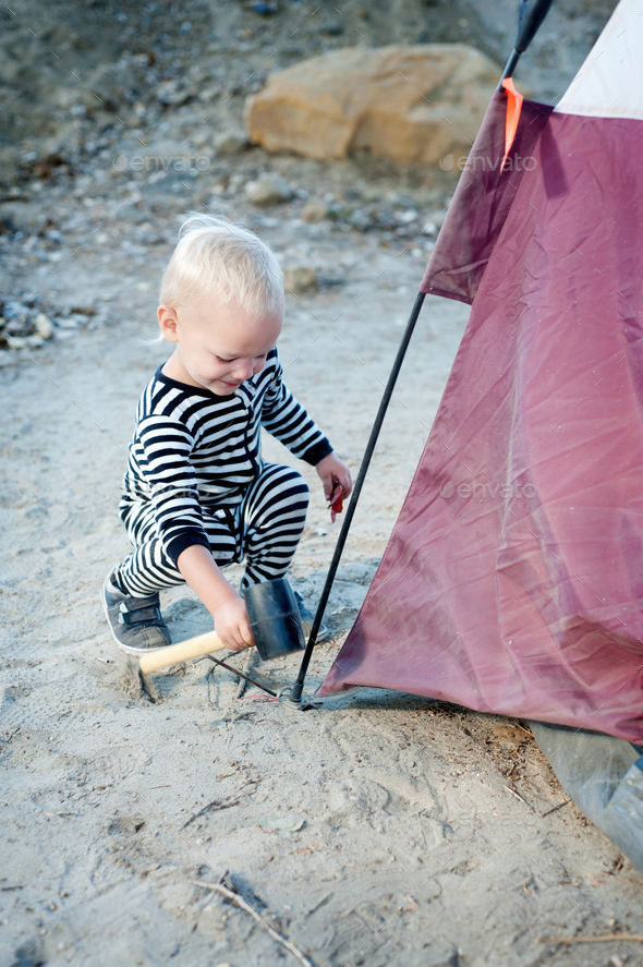 Toddler hammering tent peg with mallet