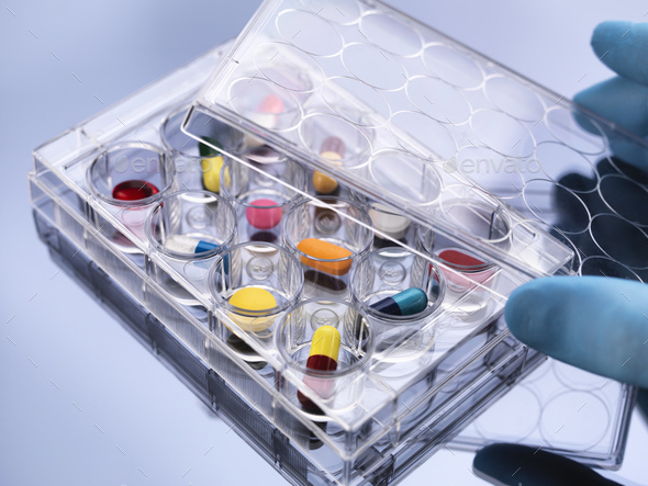 Pharmaceutical research, hand removing lid from variety of medical drugs in a multi well tray for