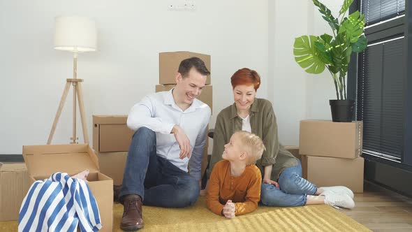 Young Family with Little Child Sit on Warm Floor Relaxing Together in Own Apartment Overjoyed Family alt