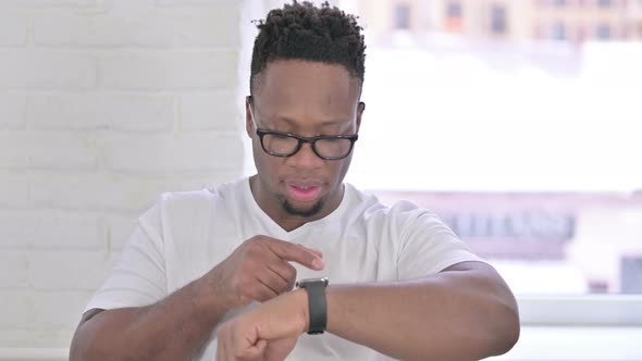 Portrait of Attractive Casual African Man Using Smartwatch  alt