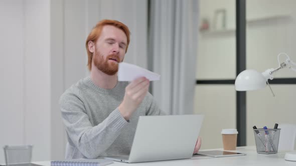 Redhead Man with Laptop Trying To Fly Paper Plane  alt