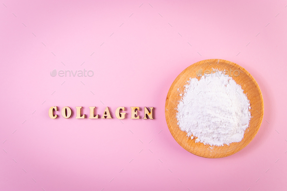 Collagen powder in wooden bowl on pink background. Natural bio supplement for skin