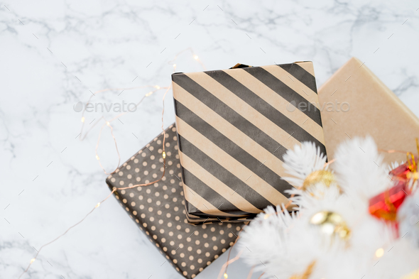 Top view of modern striped present box lay under white christmas tree