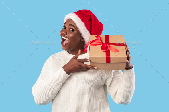 Excited Oversized Black Lady Holding Xmas Gift Over Blue Background