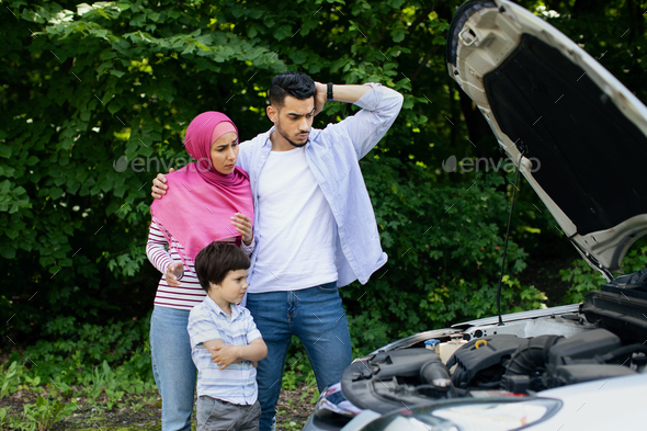 Confused Muslim Family With Little Son Standing Near Broken Car Outdoors