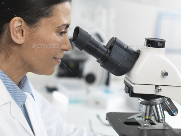 Female scientist viewing sample slide for clinical test in laboratory
