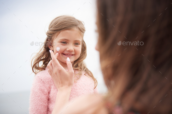 Mother applying sun cream on daughter's cheek - Stock Photo - Images