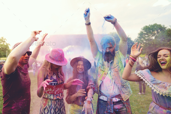 Young adult friends dancing and throwing coloured chalk powder at festival  Stock Photo by imagesourcecurated