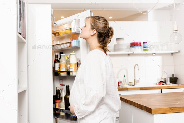Pregnant woman searching fridge for food