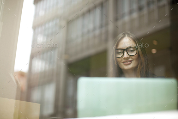 Businesswoman at cafe window using laptop, Freiburg, Germany - Stock Photo - Images