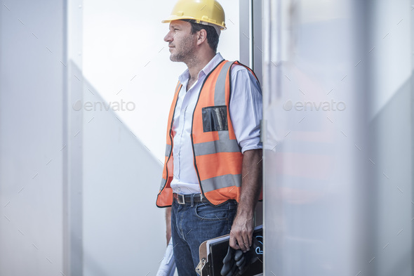 Construction foreman looking out from doorway of portable cabin on construction site