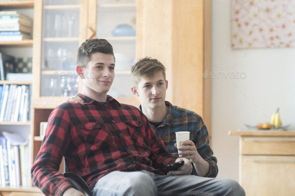 Young man using wheelchair watching tv with friend in kitchen