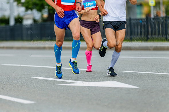 two male and one female athletes in compression socks run city marathon