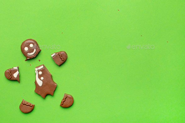 Broken chocolate figurine of a gingerbread man on a green background new year and Christmas holidays