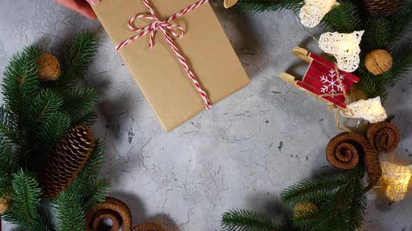 Human Female Hands Push a Gift To the Festive Decor. On the Table Are New Year and Christmas alt