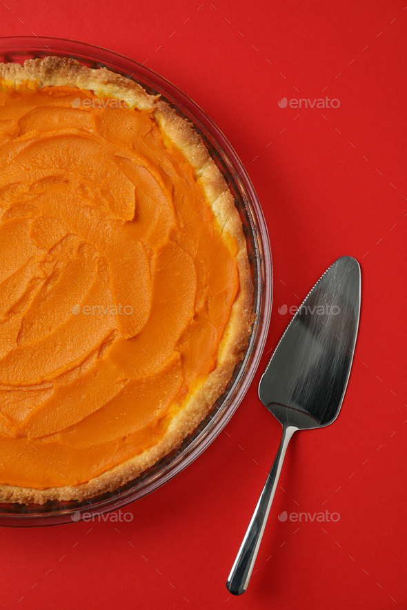 Pumpkin pie and cake spatula on red background