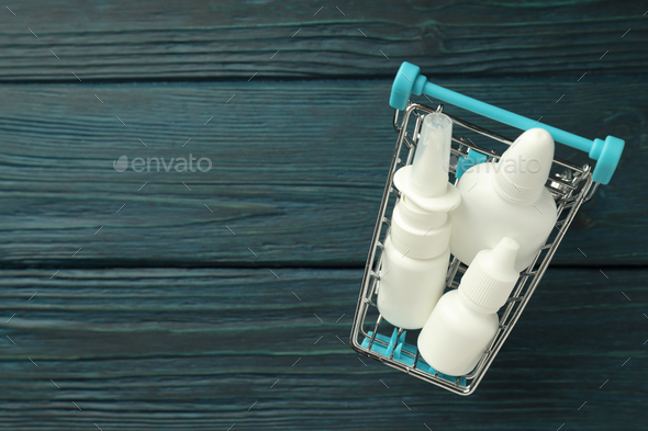 Shop trolley with bottles of nasal spray on wooden background
