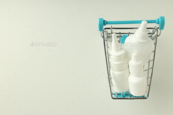 Shop trolley with bottles of nasal spray on white background