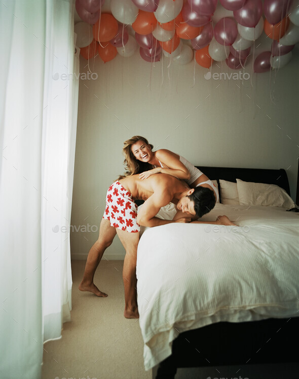 Smiling couple wrestling on bed